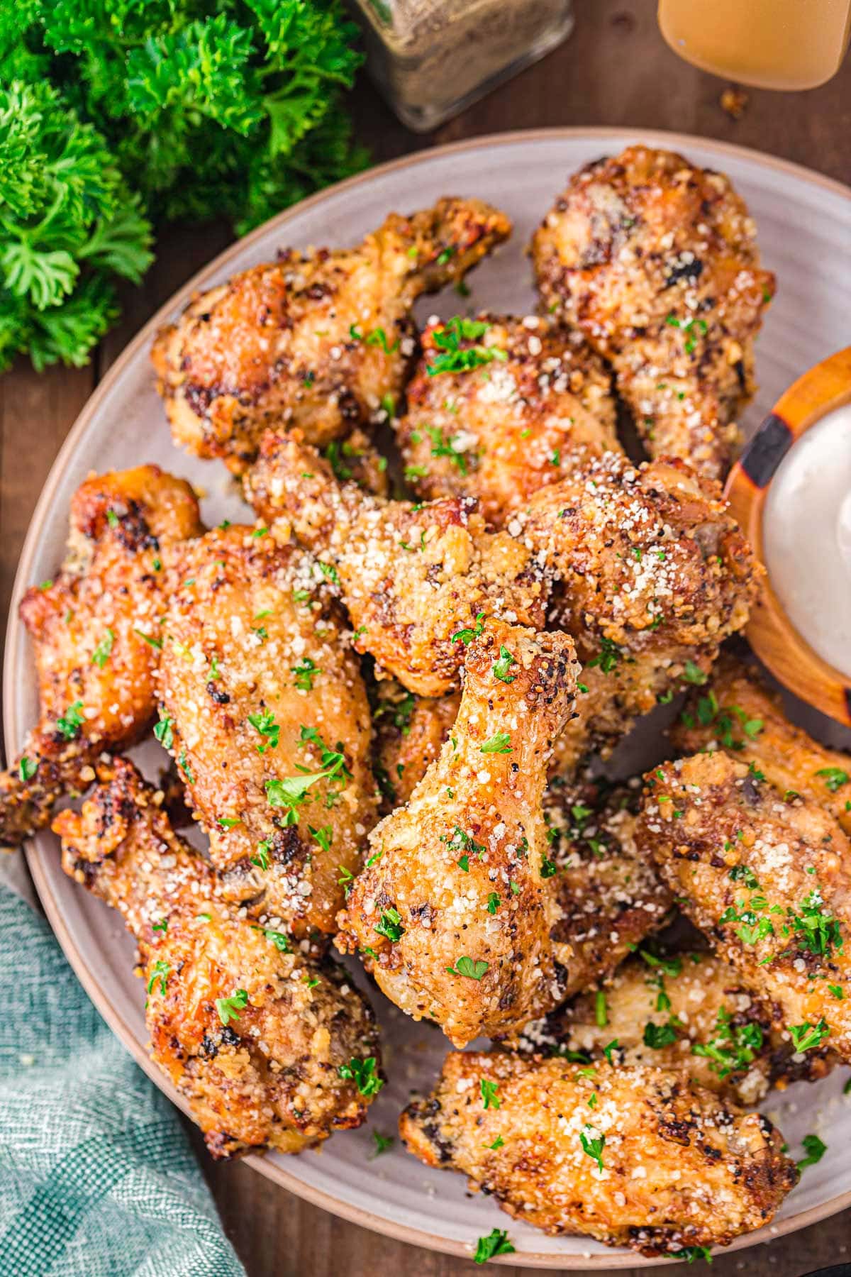 top down look at plate filled with garlic parmesan chicken wings that have been coated with Parmesan and garnished with freshly chopped parsley. 