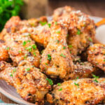 serving plate loaded with crispy golden garlic parmesan wings that have been garnished with fresh parsley.
