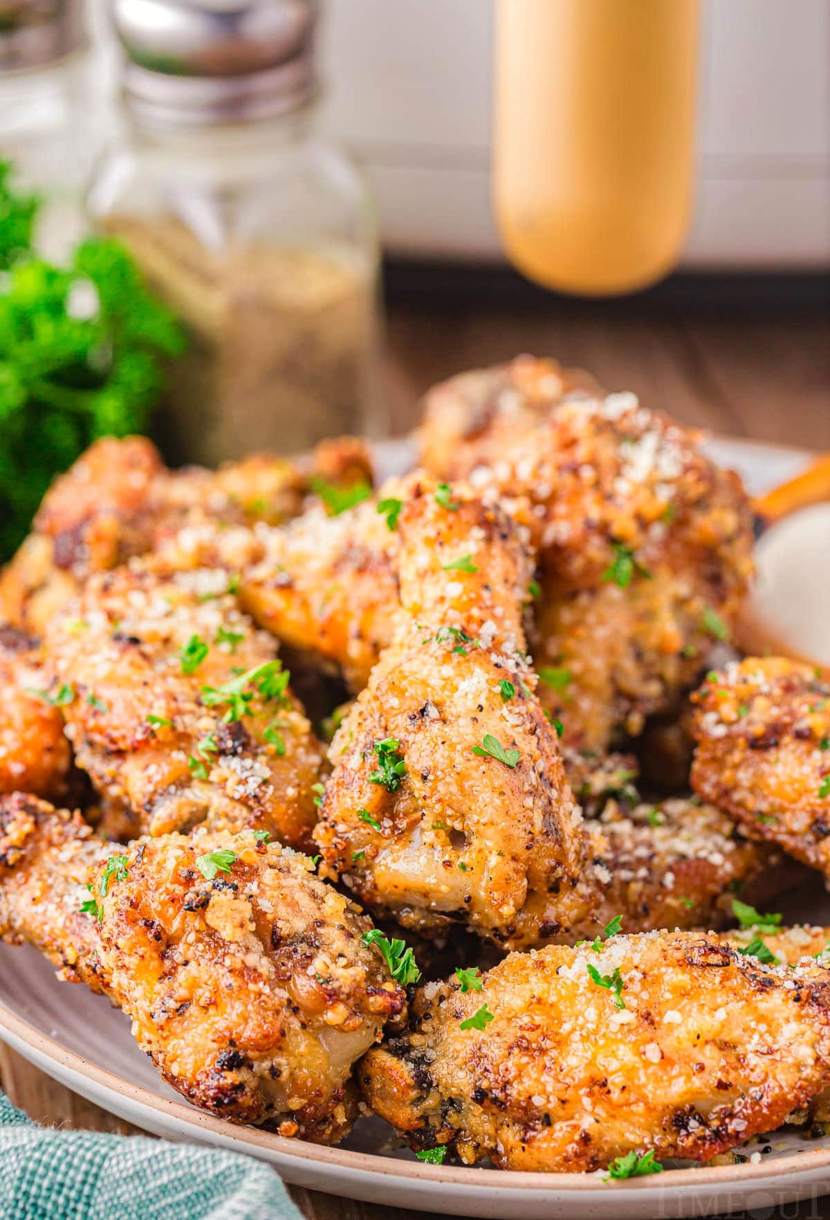 serving plate loaded with crispy golden garlic parmesan wings that have been garnished with fresh parsley.