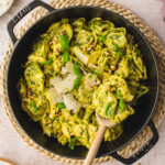 top down look at pesto tortellini in a black cast iron skillet. made with fresh basil pesto and topped with Parmesan and basil.