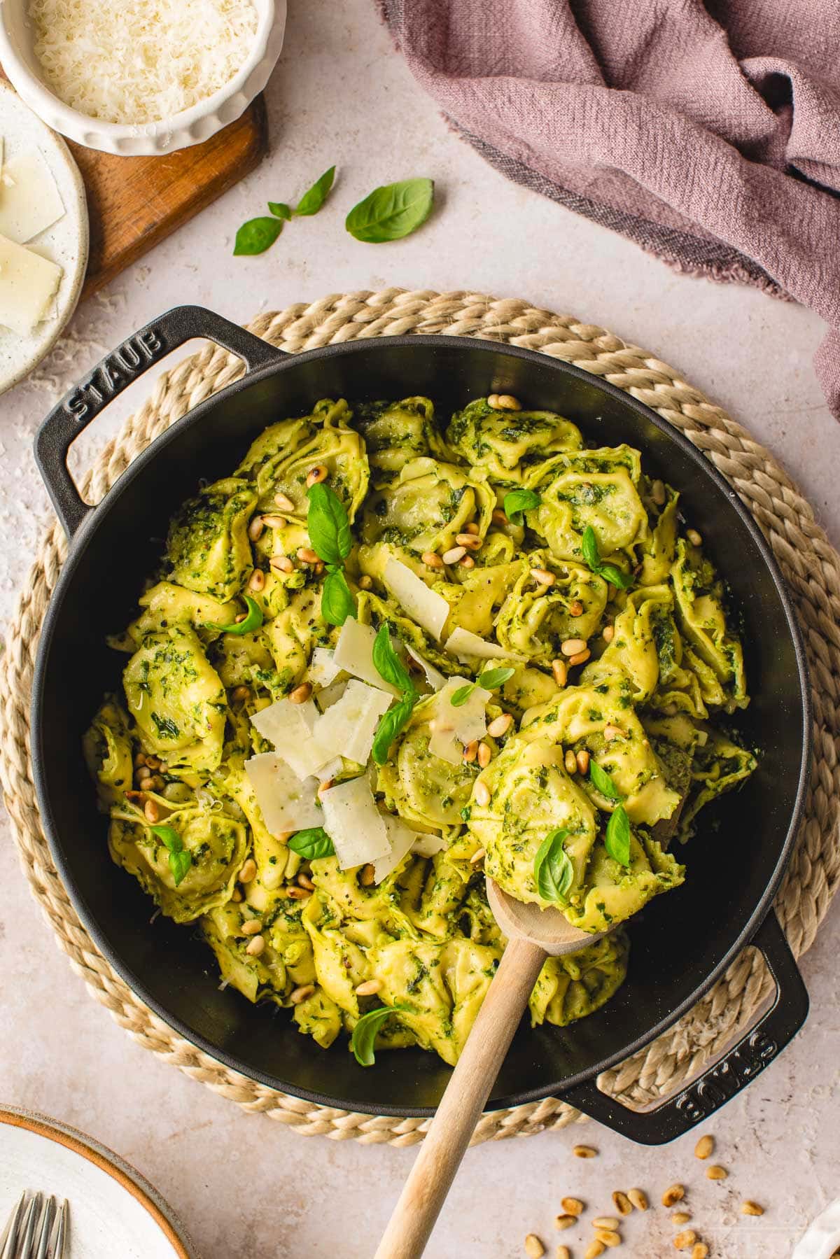 top down look at pesto tortellini in a black cast iron skillet. made with fresh basil pesto and topped with Parmesan and basil.