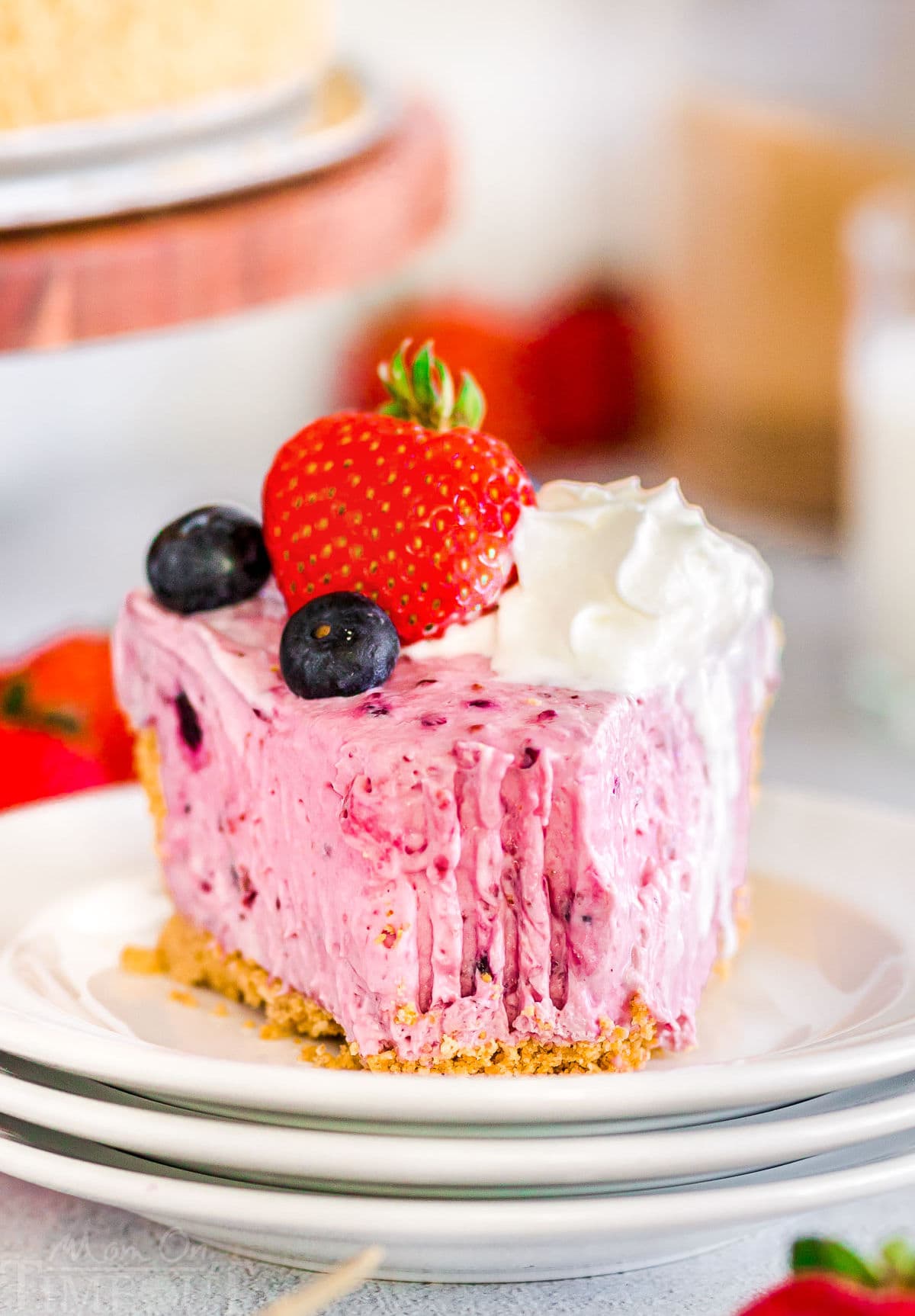 slice of no bake berry cheesecake on a small round white plate with a forkful removed from the tip.