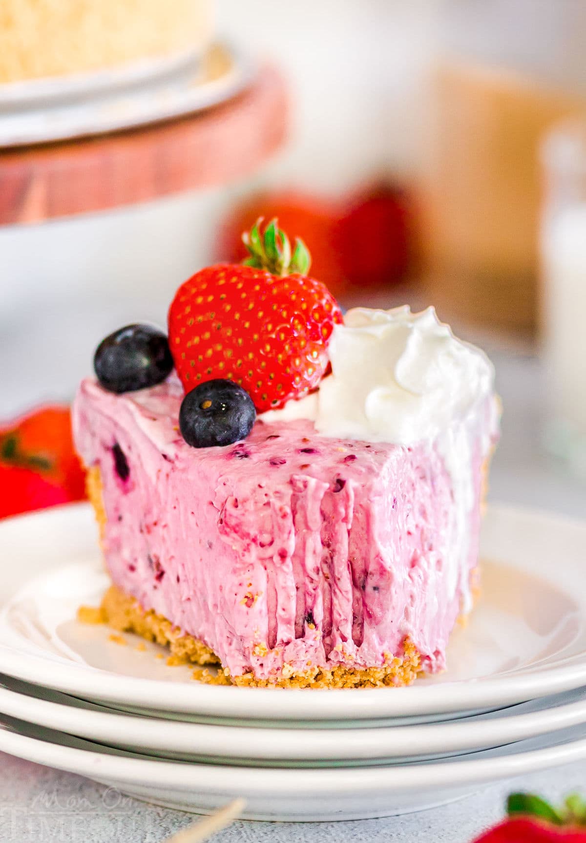 slice of no bake berry cheesecake on a small round white plate with a forkful removed from the tip. 