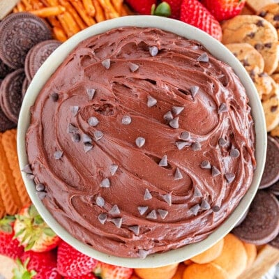 close up top down shot of a bowl of brownie batter dip surrounded by dippers including fresh strawberries, nilla wafers, pretzels and cookies.