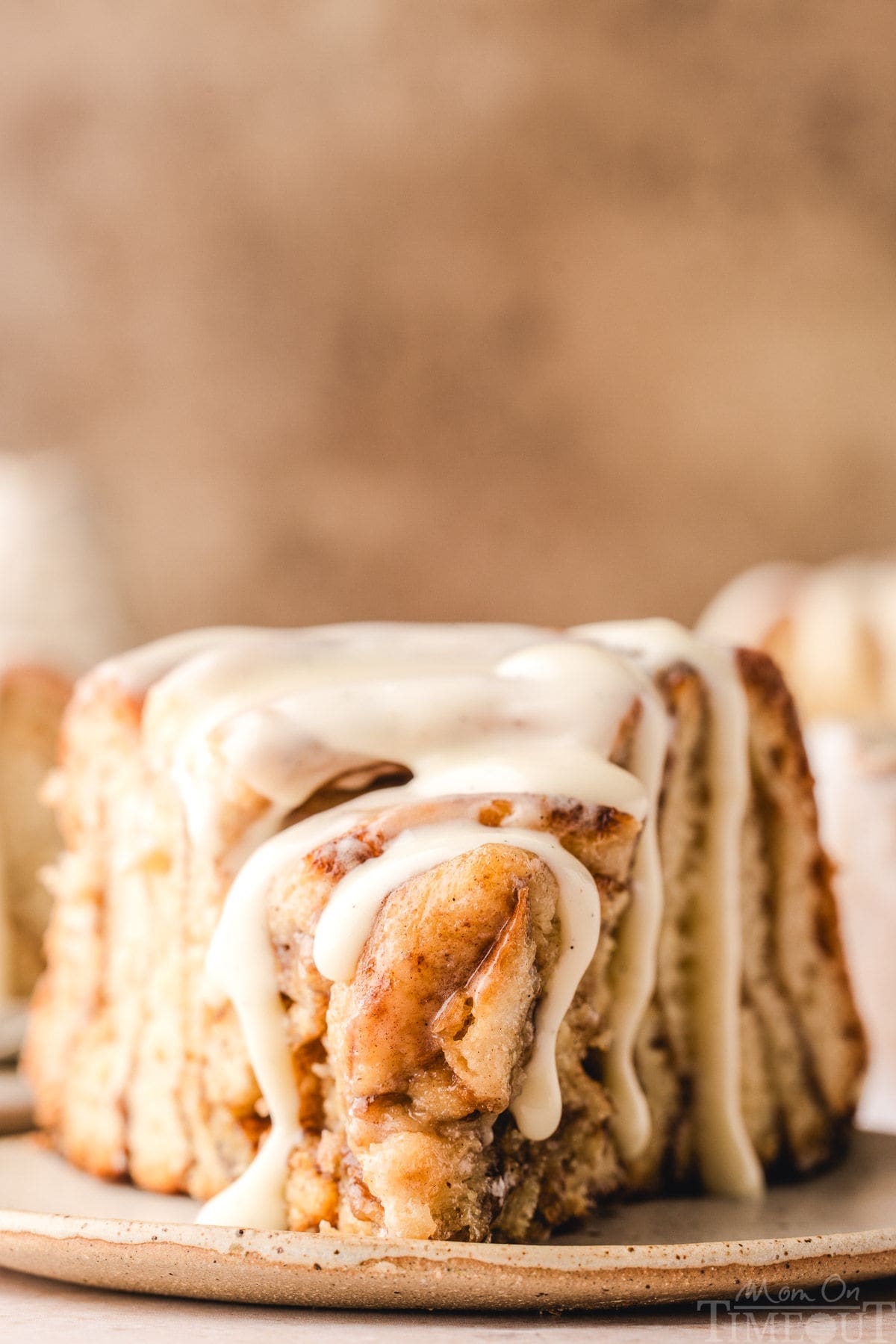 Slice of giant cinnamon roll cake recipe on small white plate. Cake has been drizzled with cream cheese glaze.