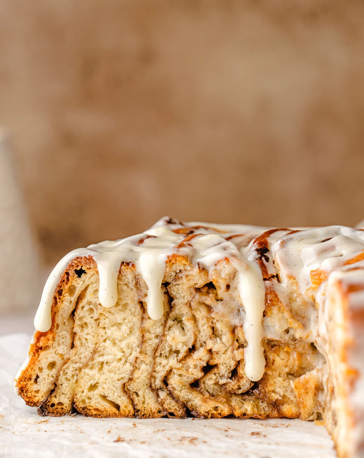 cross sectional view of the cinnamon roll cake showing all the swirls of cinnamon sugar filling with the glaze dripping down the sides of the cake.