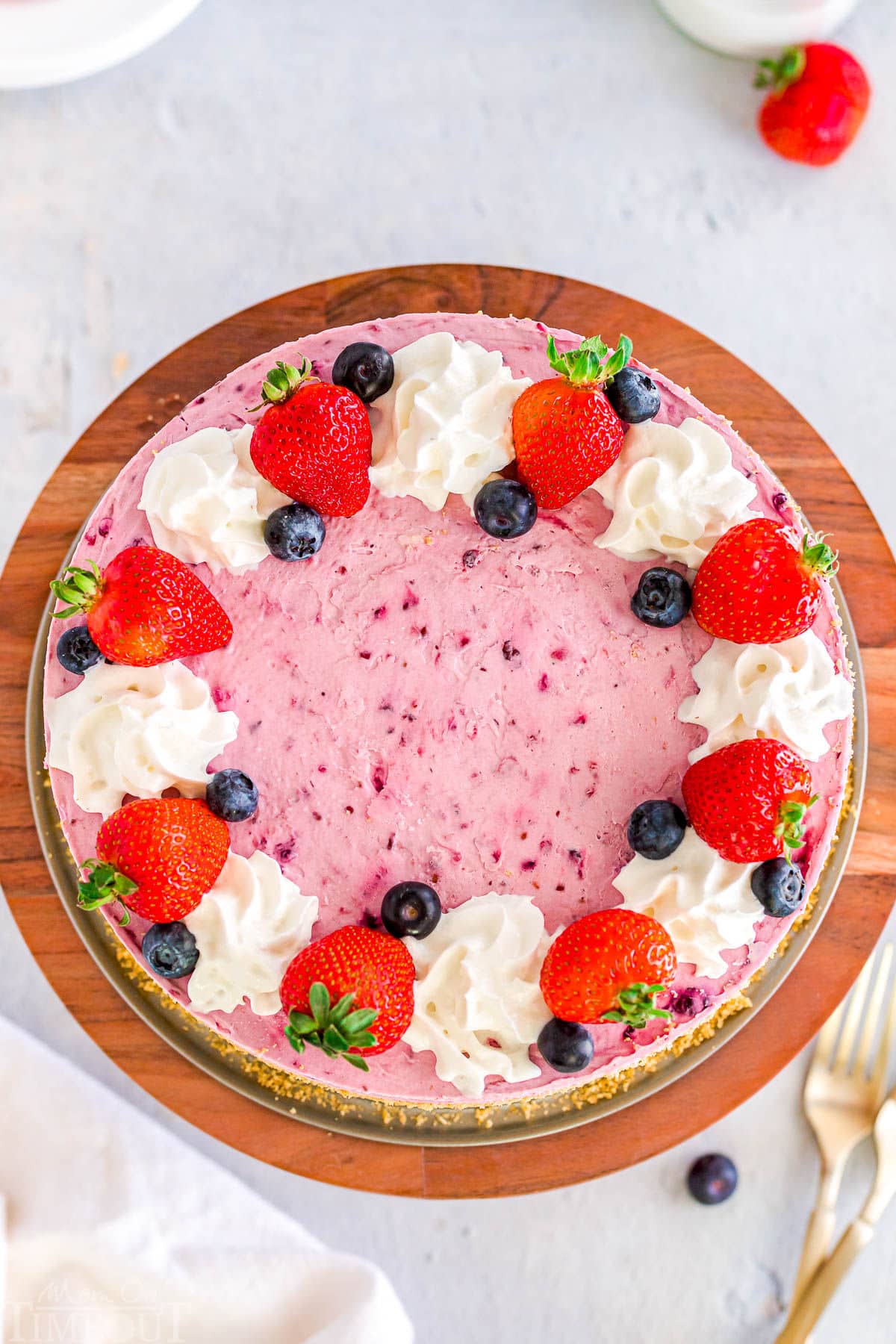 top down view of berry cheesecake decorated with fresh berries and whipped cream.