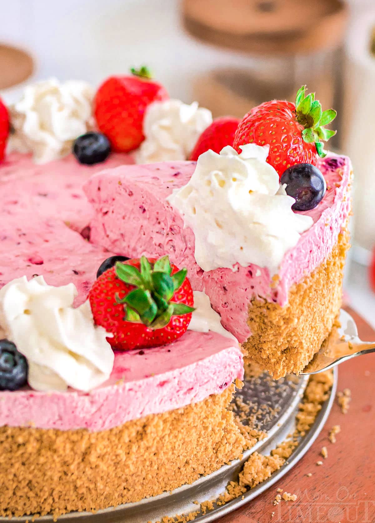 slice of berry cheesecake being lifted away from the rest of the cheesecake.