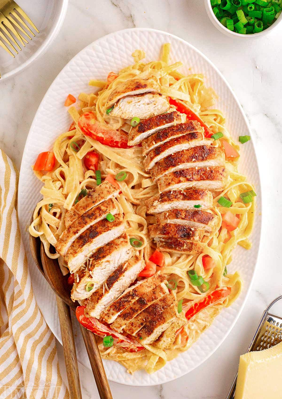 top down look at large white platter topped with pasta and cajun chicken.