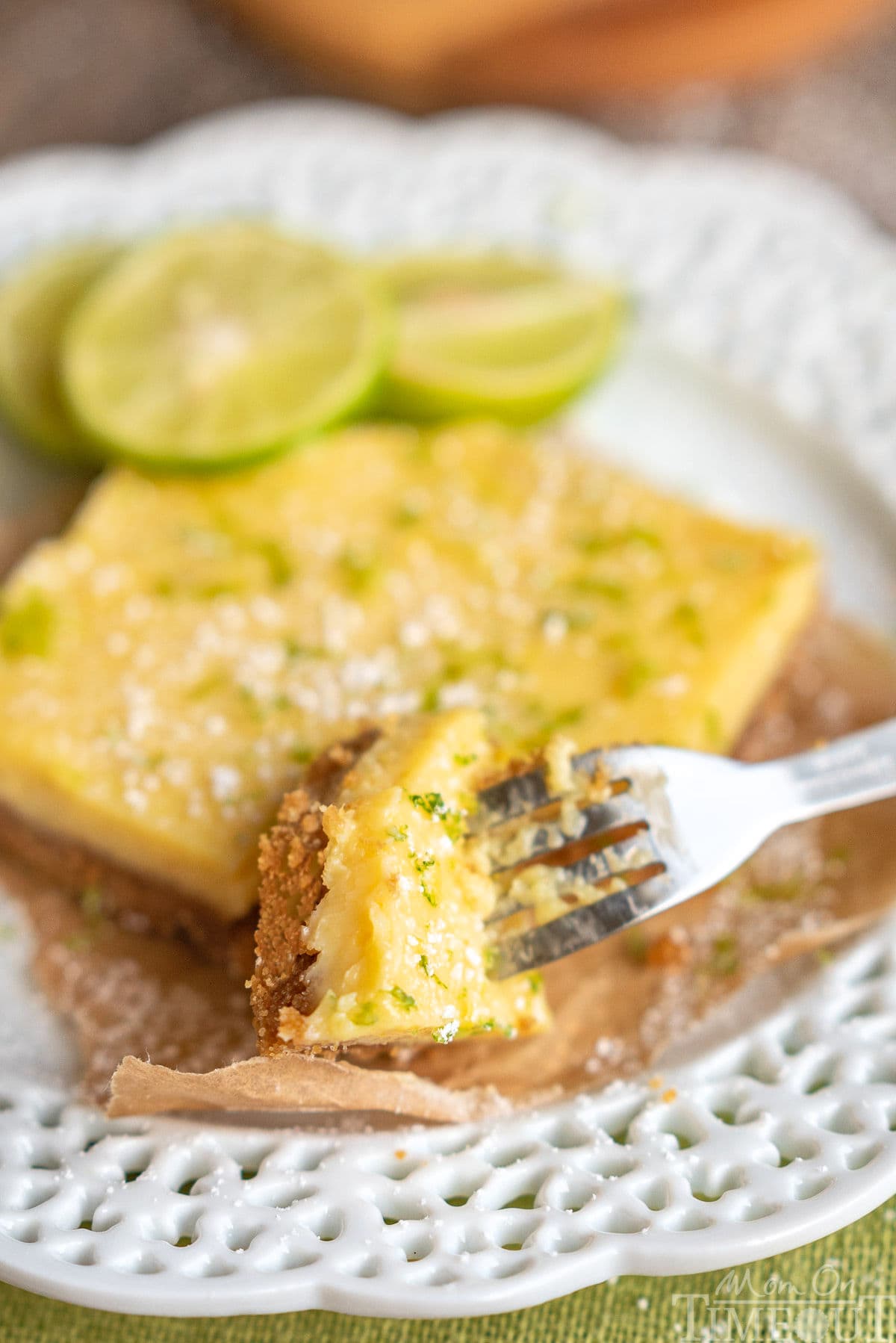 key lime pie bar on white plate with a corner cut off with a fork. 