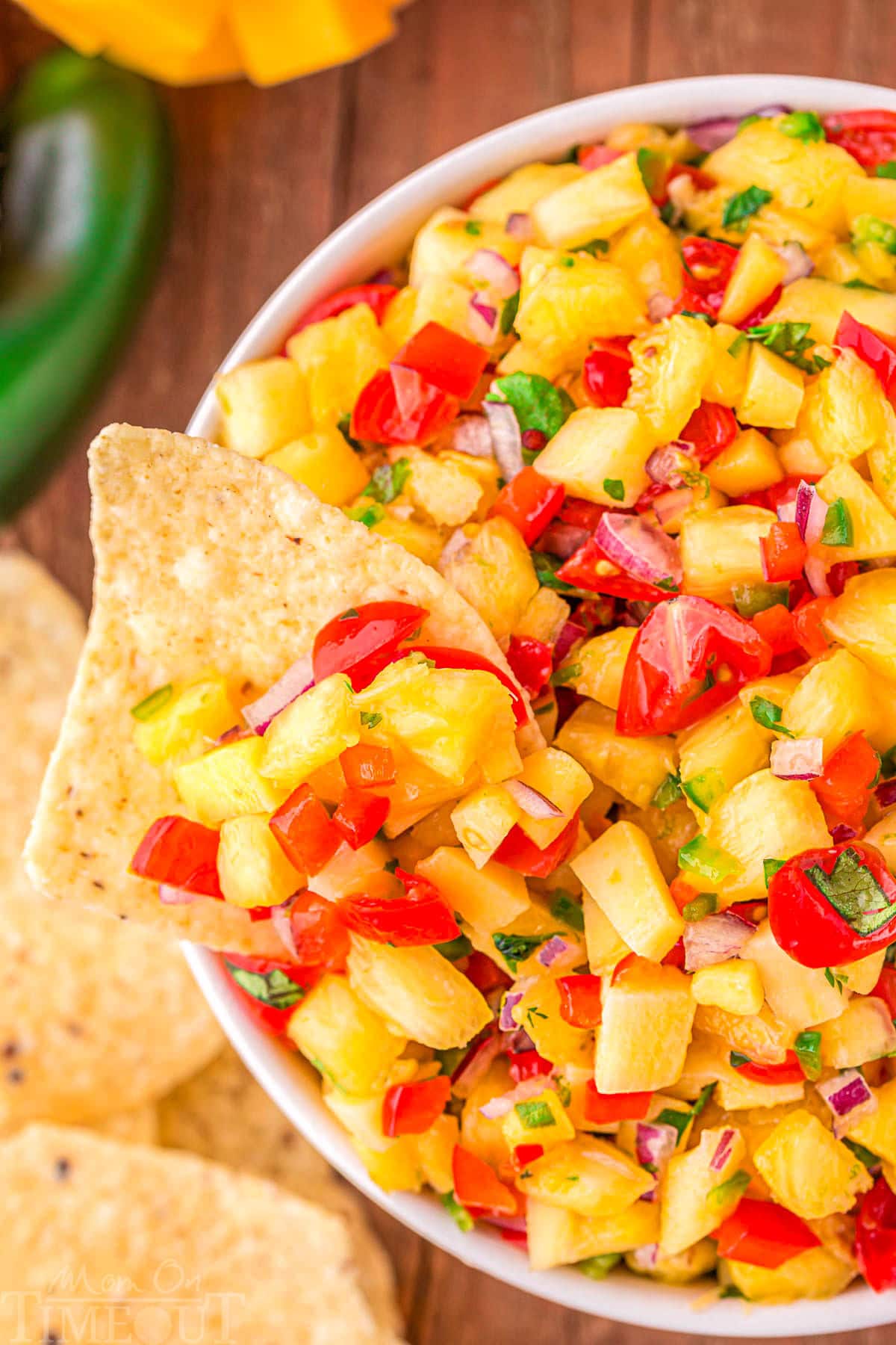 bowl of pineapple mango salsa with a chip dipped into the bowl.