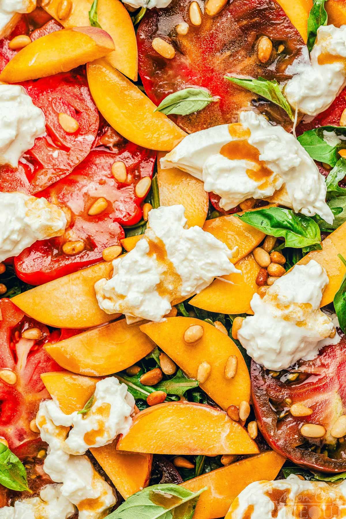 Persikų pomidorų salotos ant lėkštės iš arti. Persikų ir pomidorų griežinėliai ant rukolos su burrata sūriu ir balzamiko padažu.