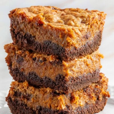 A stack of chocolate pumpkin cheesecake bars on a white plate.