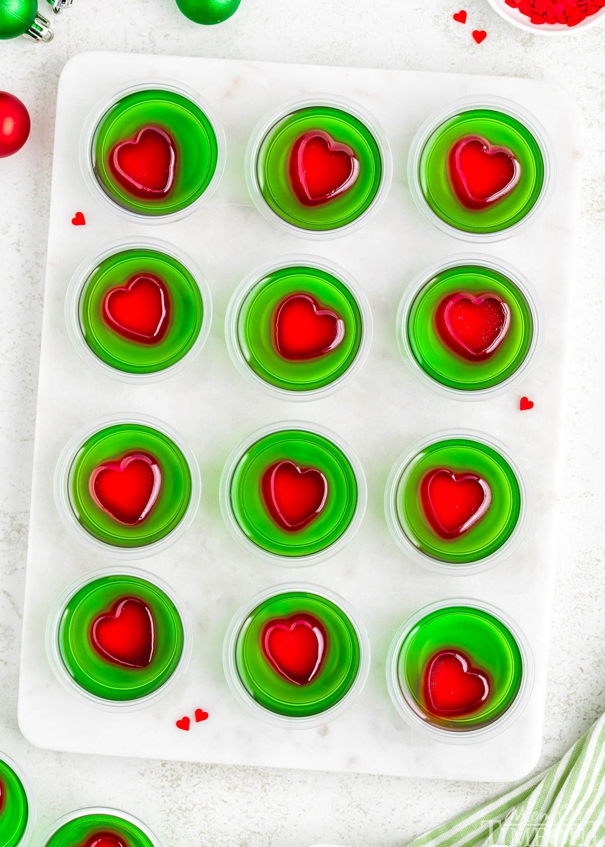A top down view of Grinch Jello Shots lined up on a marble cutting board.