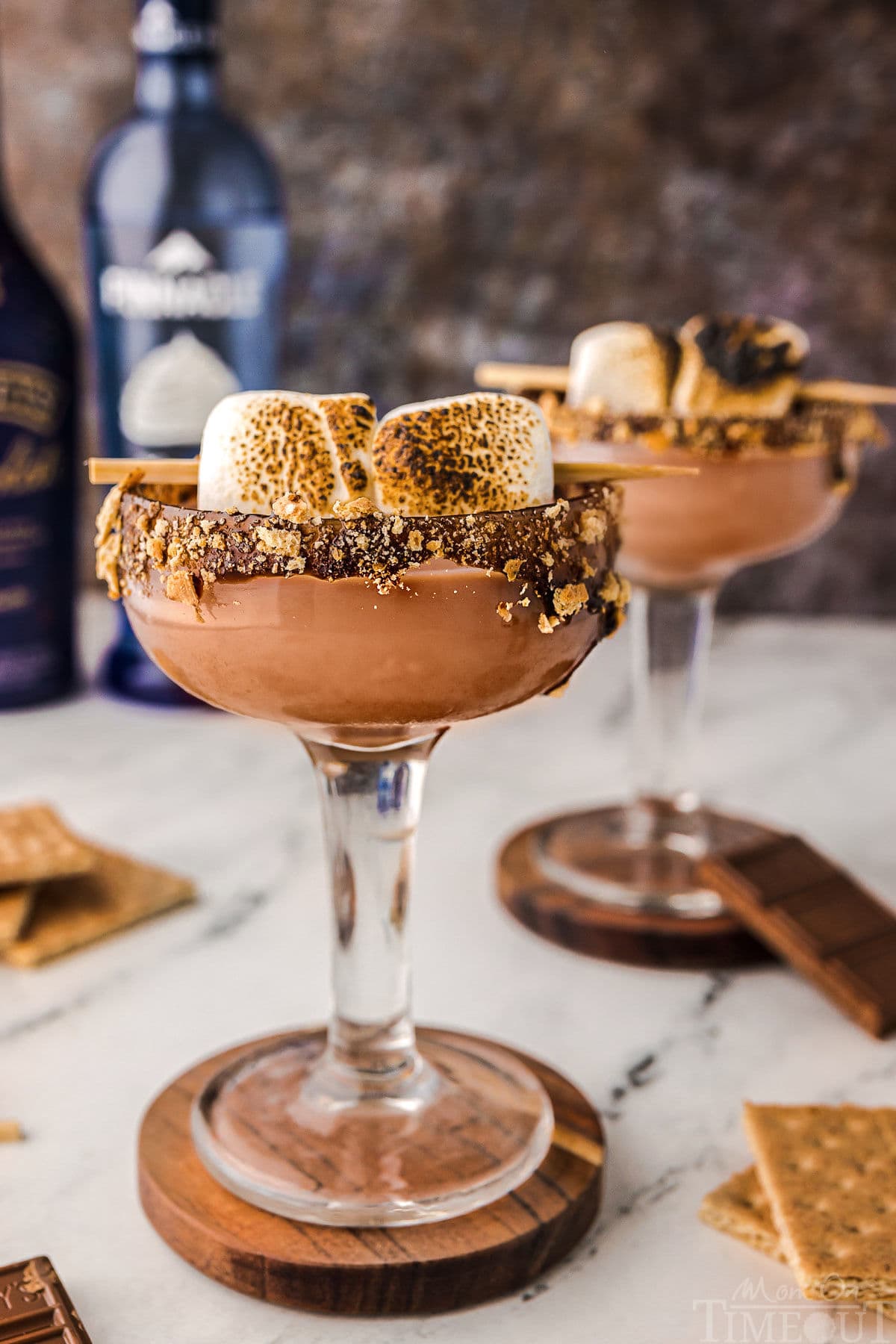 Two Smores martini with toasted marshmallow garnish and chocolate and graham cracker rim sitting on coasters ready to be enjoyed.