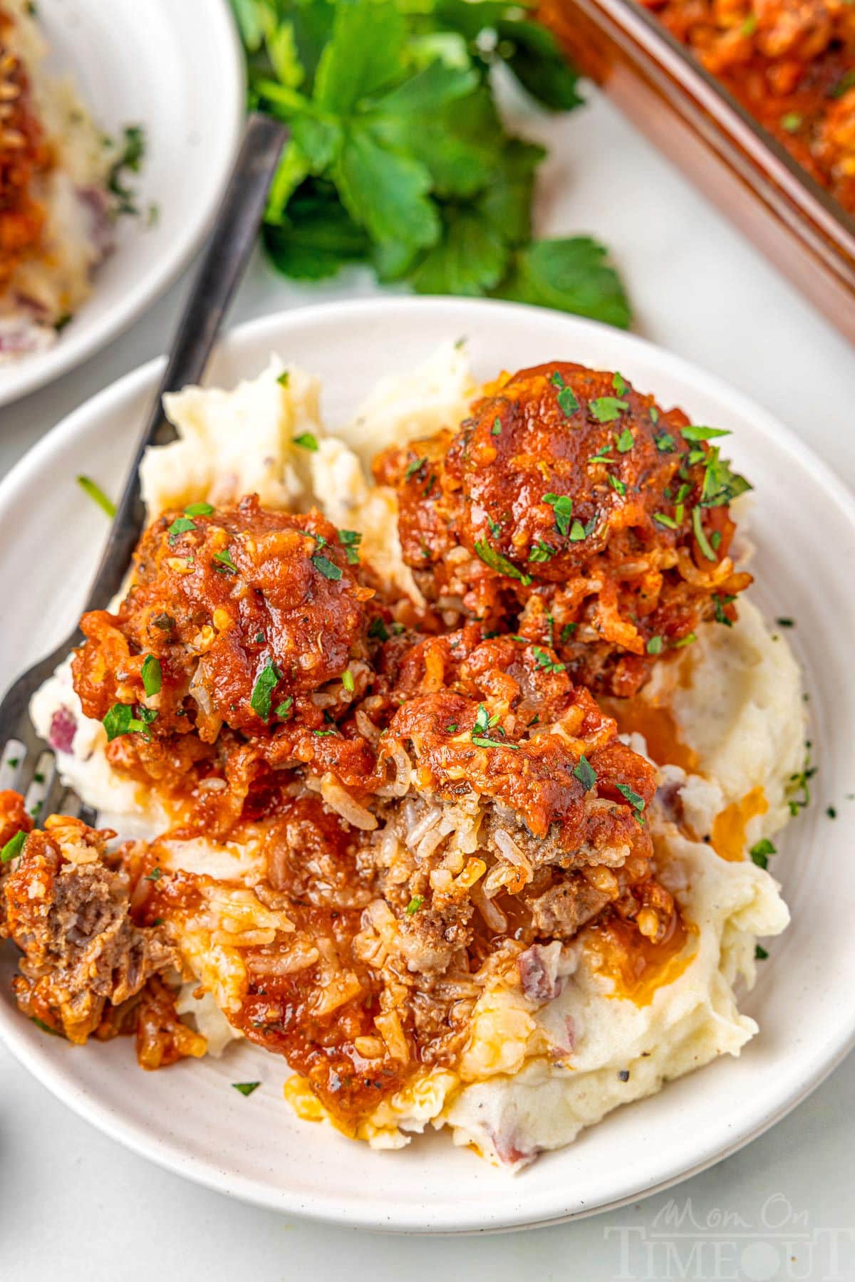 3 meatballs on a bed of mashed potatoes on a white plate.