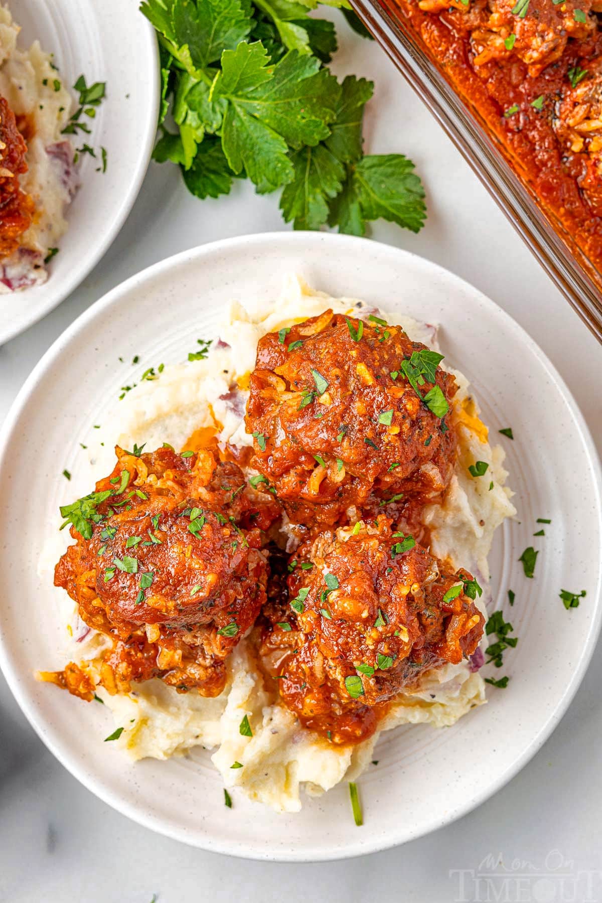 Three porcupine meatballs on a round white plate topped with parsley.