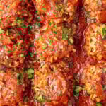 Porcupine Meatballs with fresh parsley sprinkled on top. The meatballs are lined up in a baking pan.