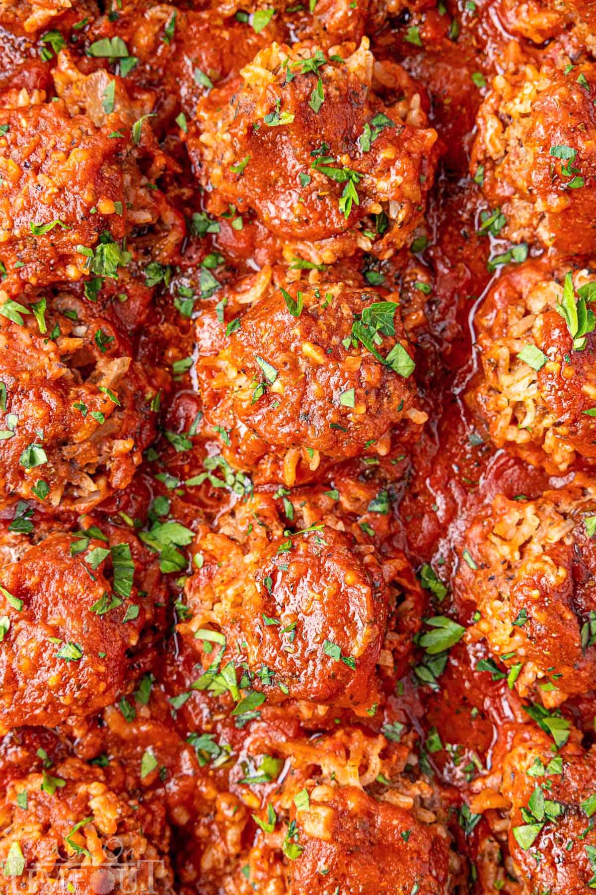Porcupine Meatballs with fresh parsley sprinkled on top. The meatballs are lined up in a baking pan.