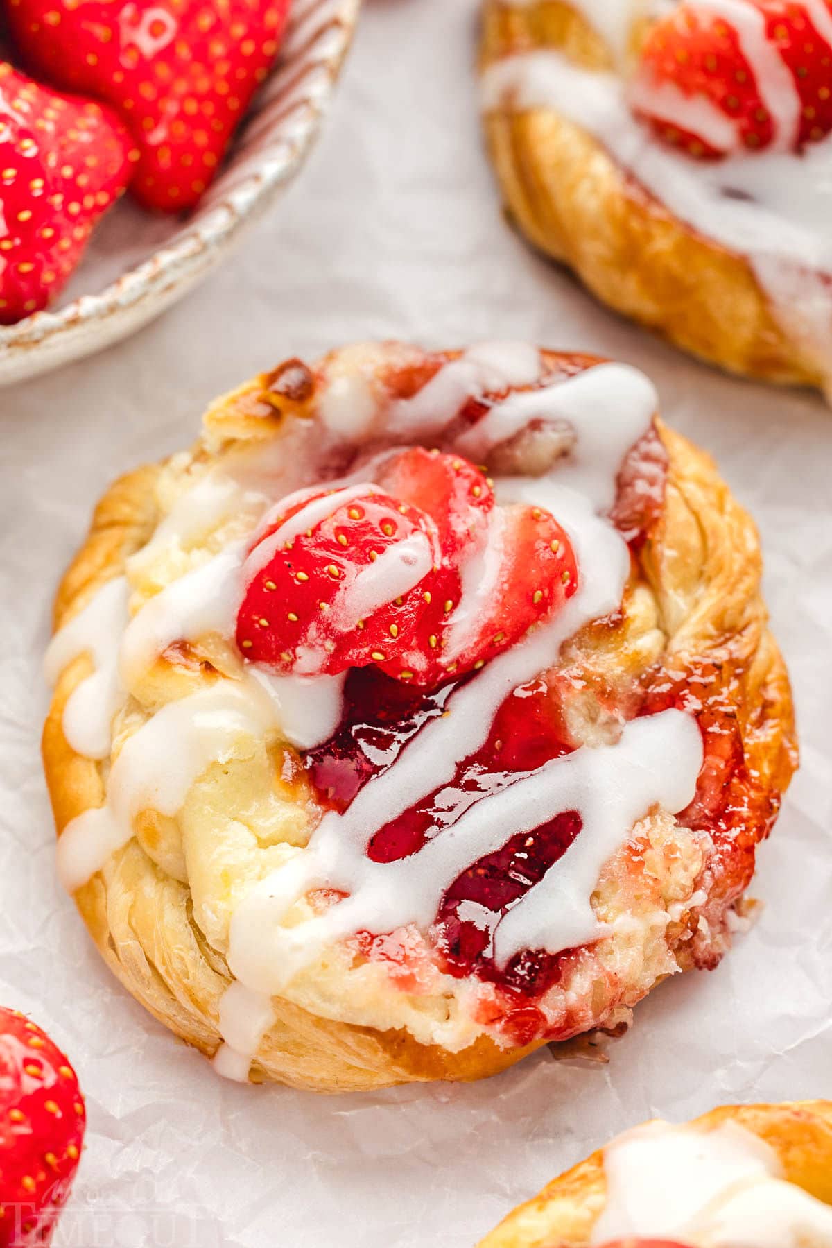 Close up of Strawberry danish with cream cheese topped with a glaze and fresh strawberries.