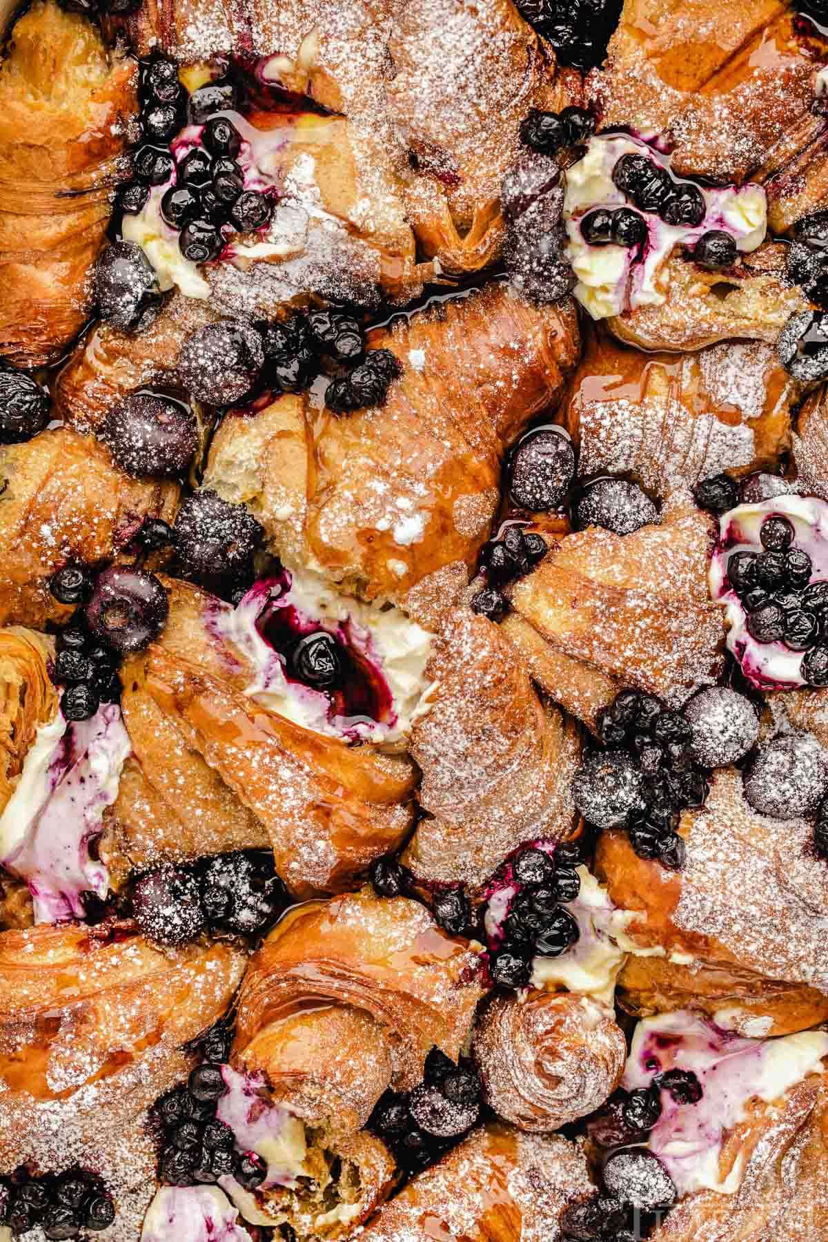 Close up look at french toast bake made with croissants and blueberries in baking dish.