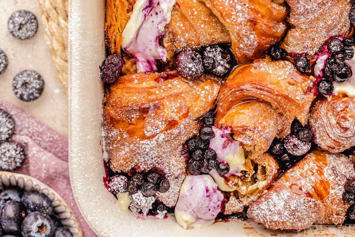 Wide look at the corner of the baking dish with freshly baked blueberry croissant french toast bake recipe. Blueberries can be seen on the side of the baking dish.