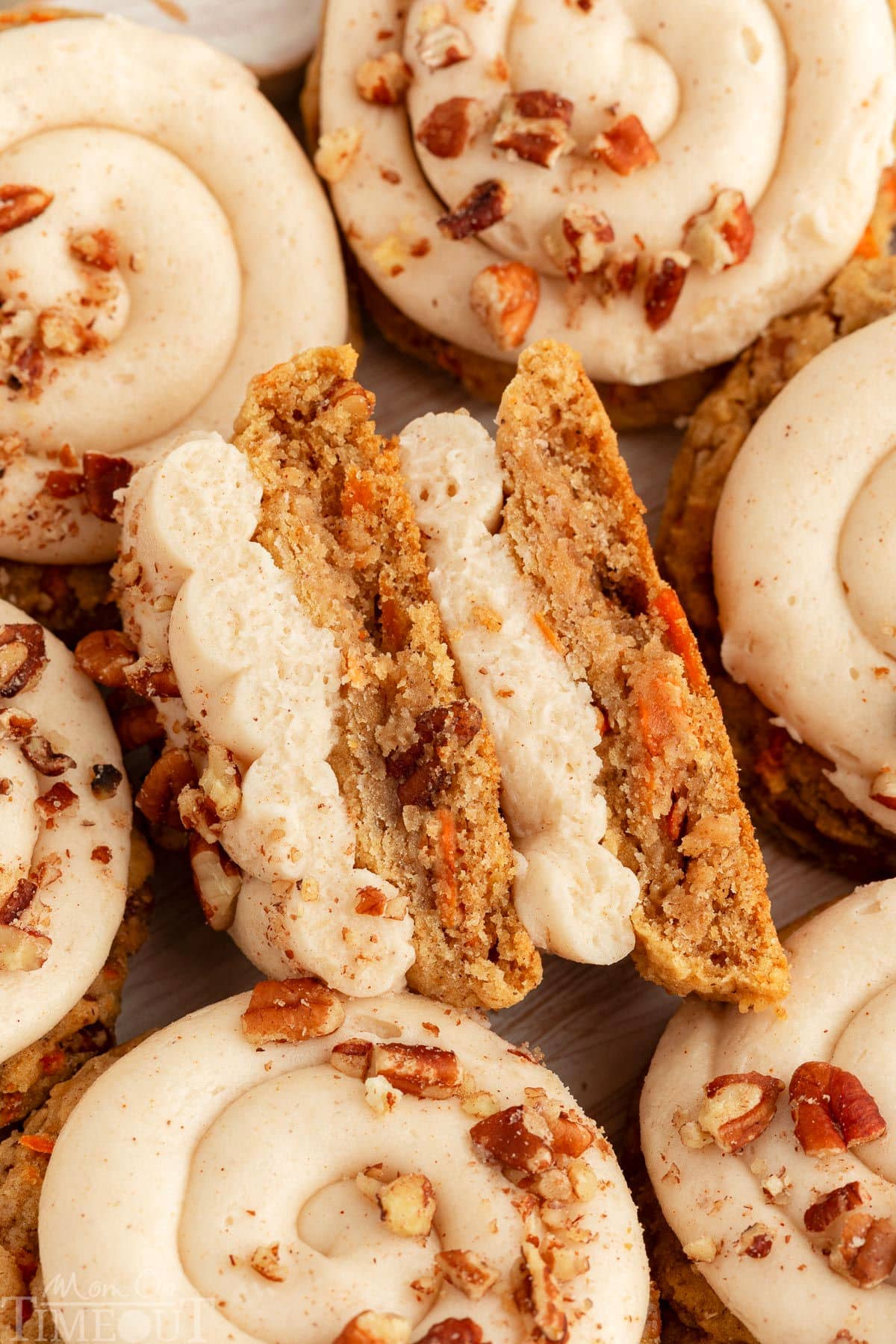 A carrot cake cookie cut in half to show the texture. Extra cookies are placed around it.