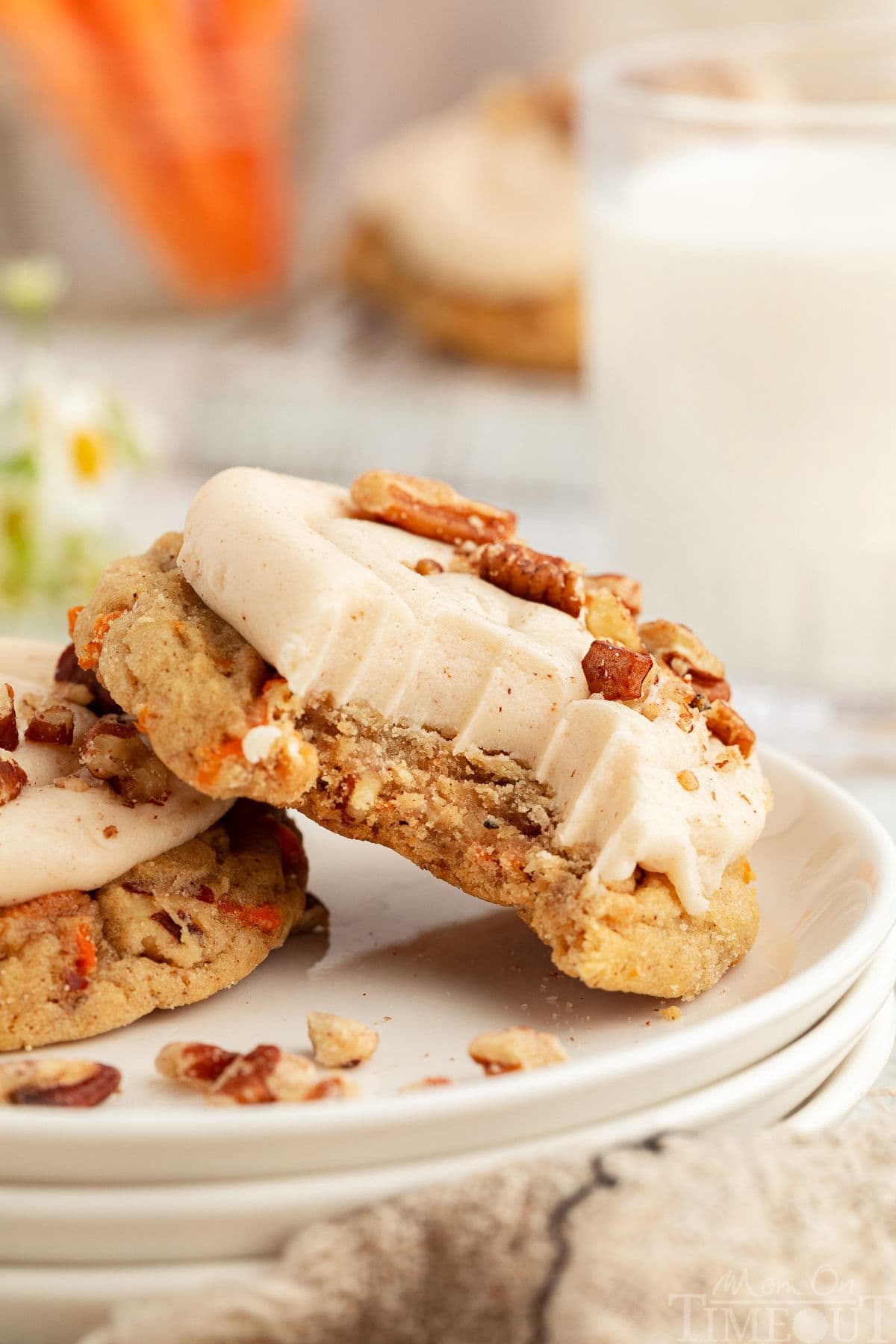 Carrot Cake Cookie with a bite taken out of it. The cookie leaning against another cookie on a white plate.