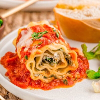 Lasagna Roll Ups plated with salad and bread on a dinner plate.
