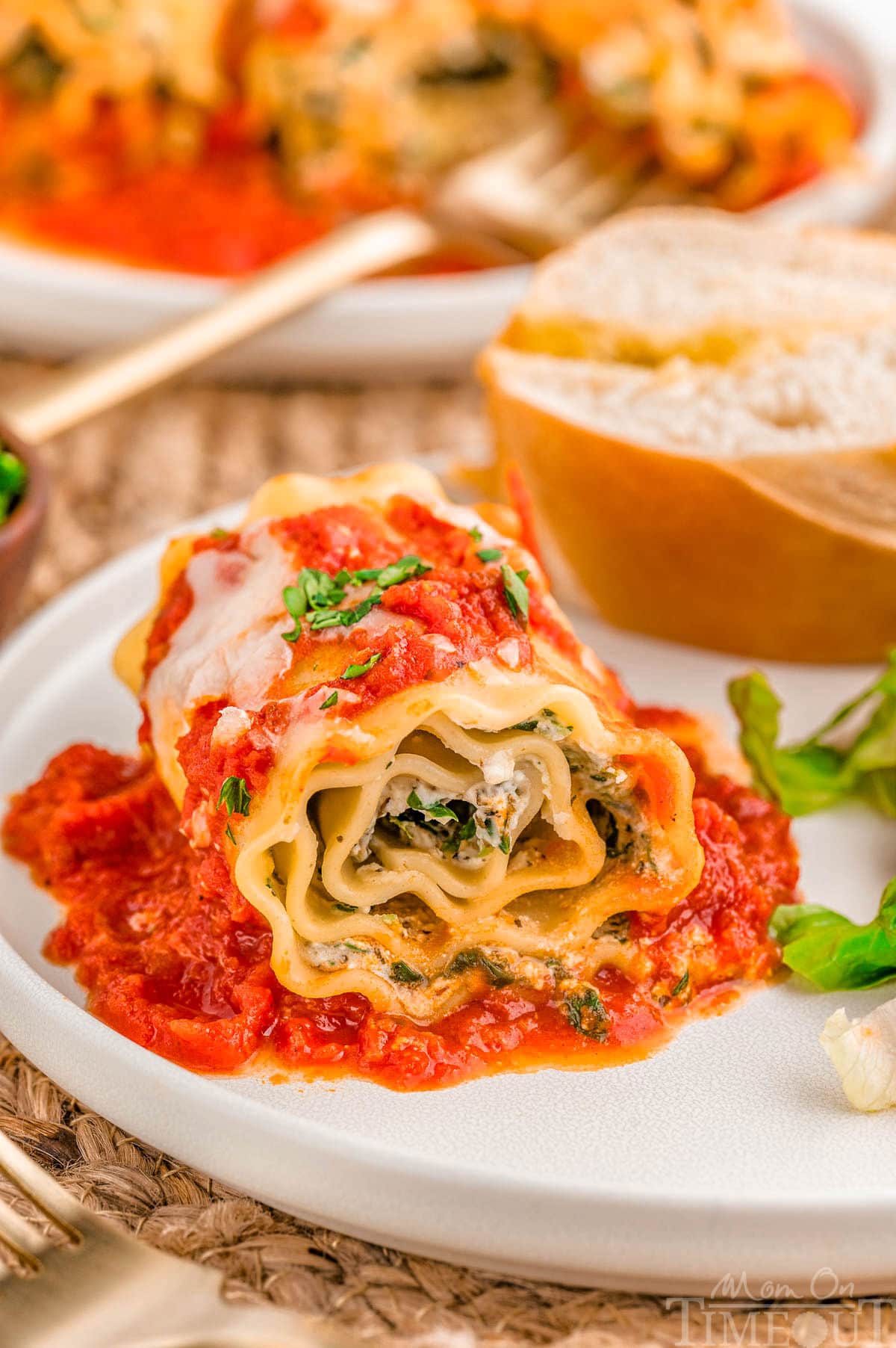 Lasagna Roll Ups plated with salad and bread on a dinner plate.