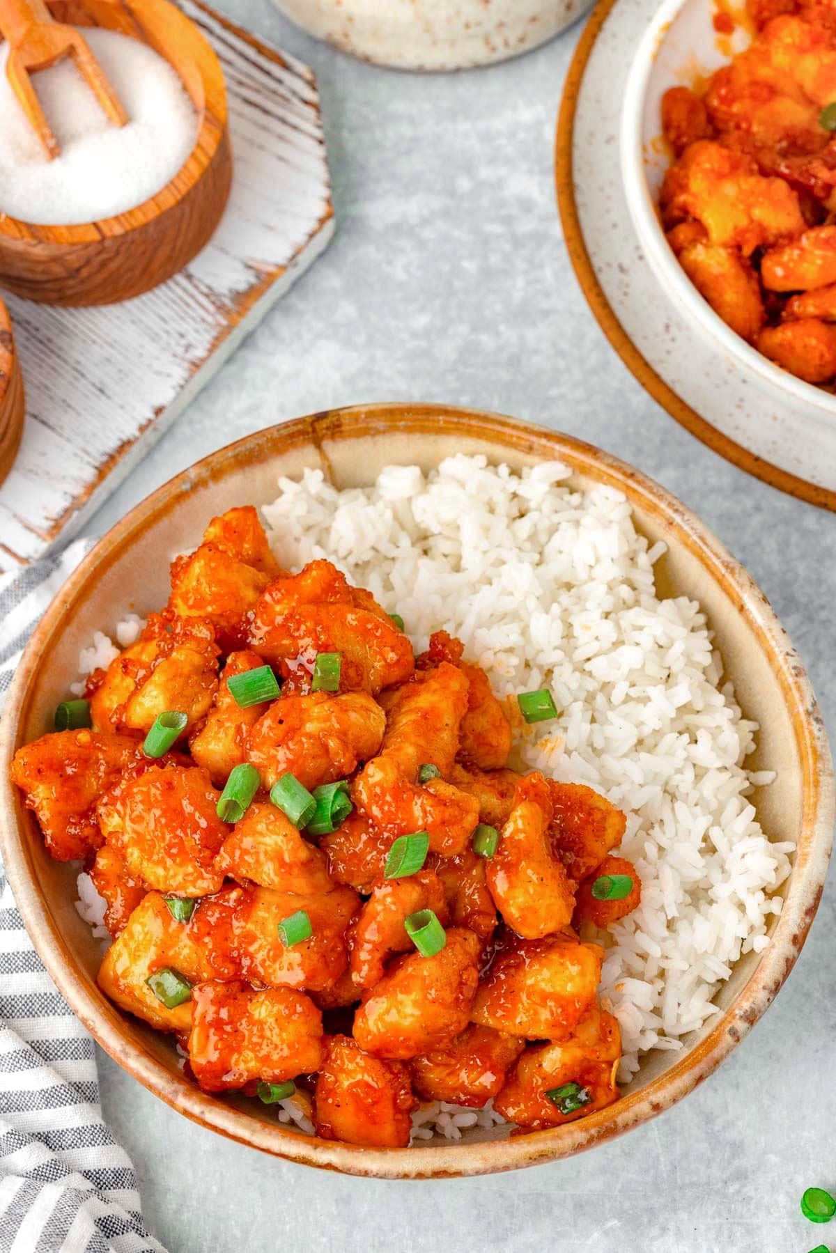 Top down view of bowl of white rice and Firecracker Chicken recipe with a towel next to it.