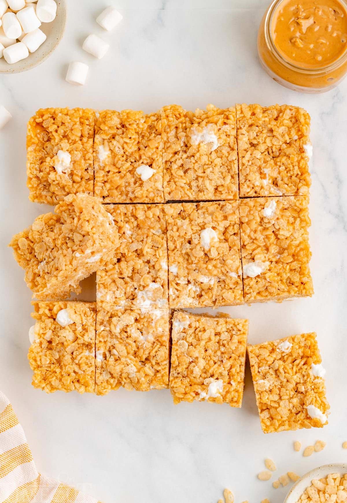 Top down view of rice krispie treats cut into squares on white surface.