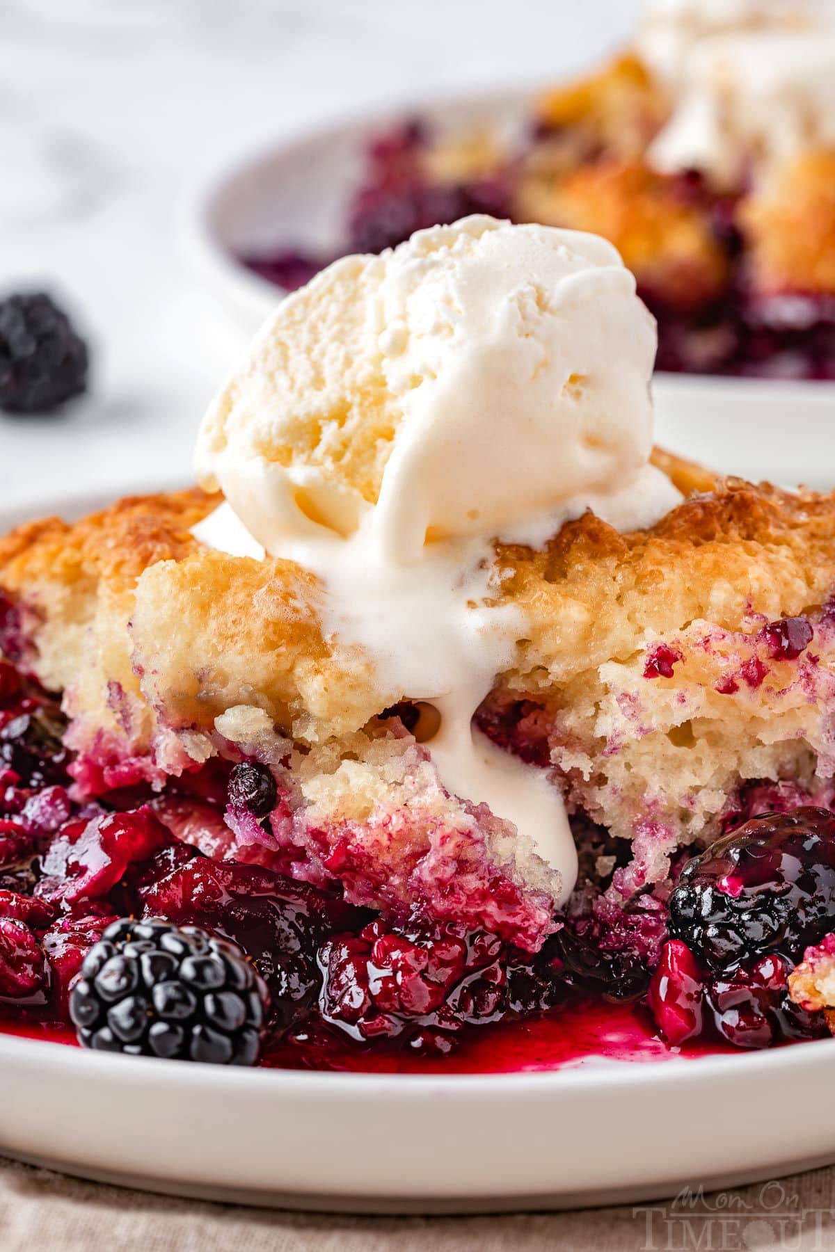 Close up of berry cobbler on plate topped with ice cream.