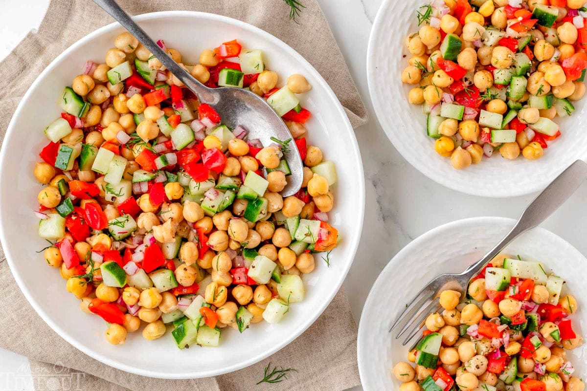 Wide shot of three plates with chickpeas salad recipe served on them.