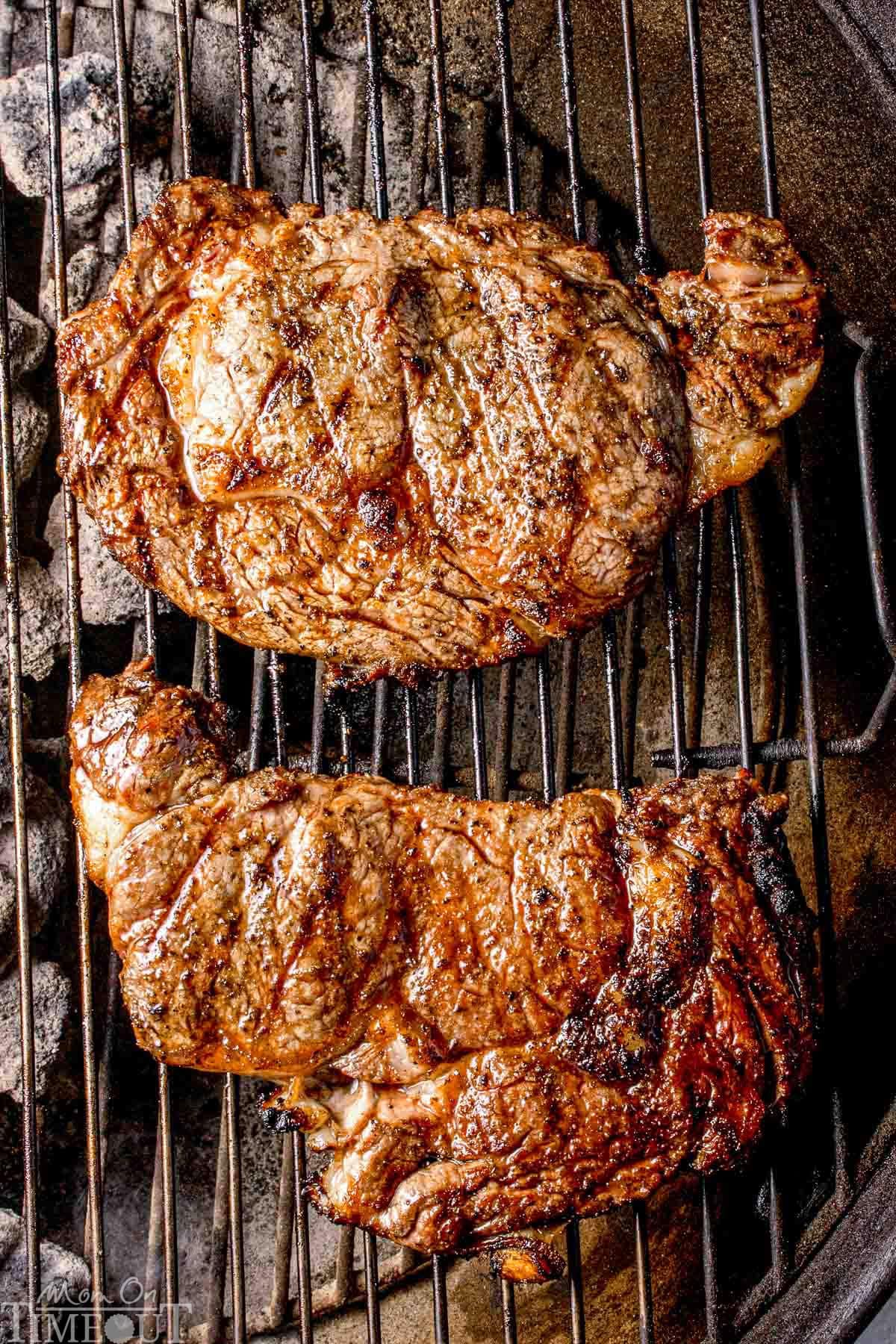 Overhead shot of two ribeye steaks on grill.