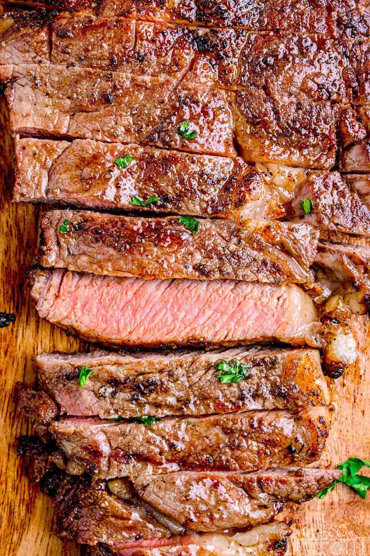Grilled ribeye cut into strips with one strip turned on it's side to show the medium interior.