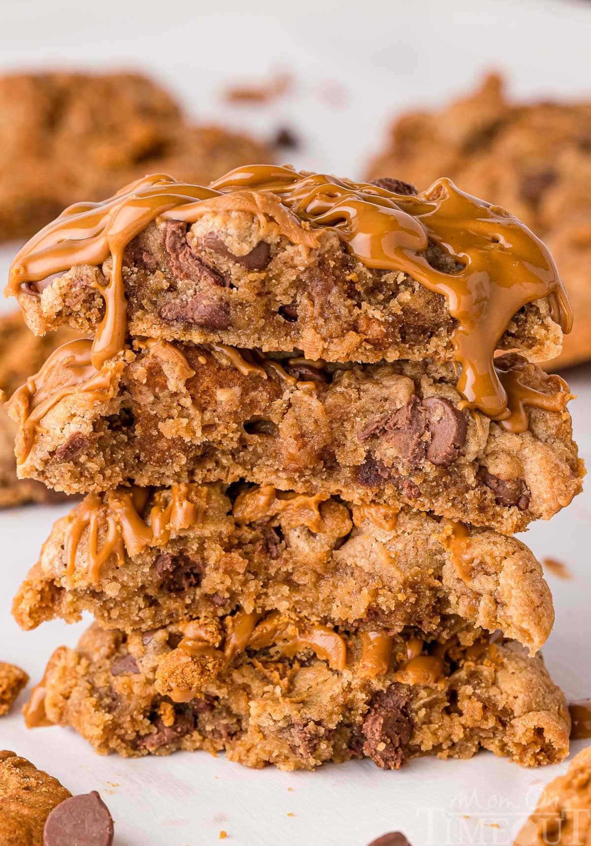 Stack of four biscoff chocolate chip cookies topped with cookie butter stacked on white parchment.