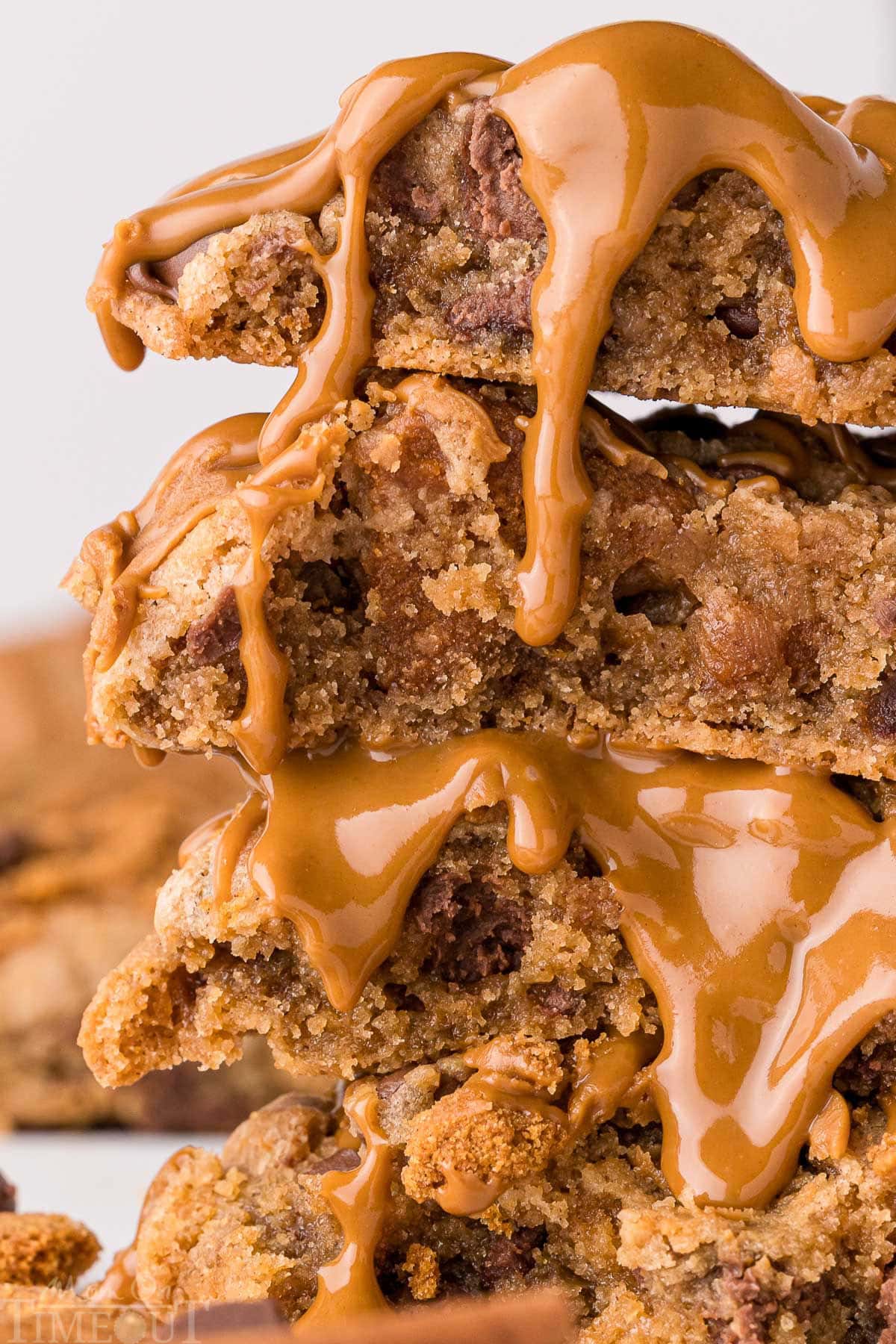 Close up look at chocolate chip biscoff cookies torn in half and stacked four high. Topped with a drizzle of cookie butter.