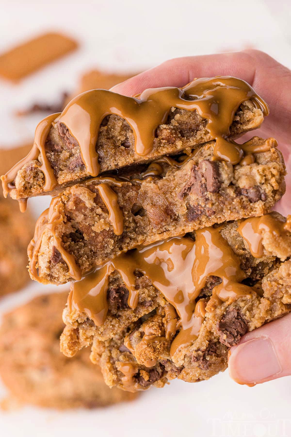 Two biscoff cookies broken in half and topped with cookie butter held in a hand.