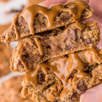 Two biscoff cookies broken in half and topped with cookie butter held in a hand.