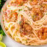 Close up look at bowl of cajun shrimp pasta recipe with a rich Parmesan cream sauce and topped with spicy shrimp and garnished with fresh parsley and Parmesan cheese.