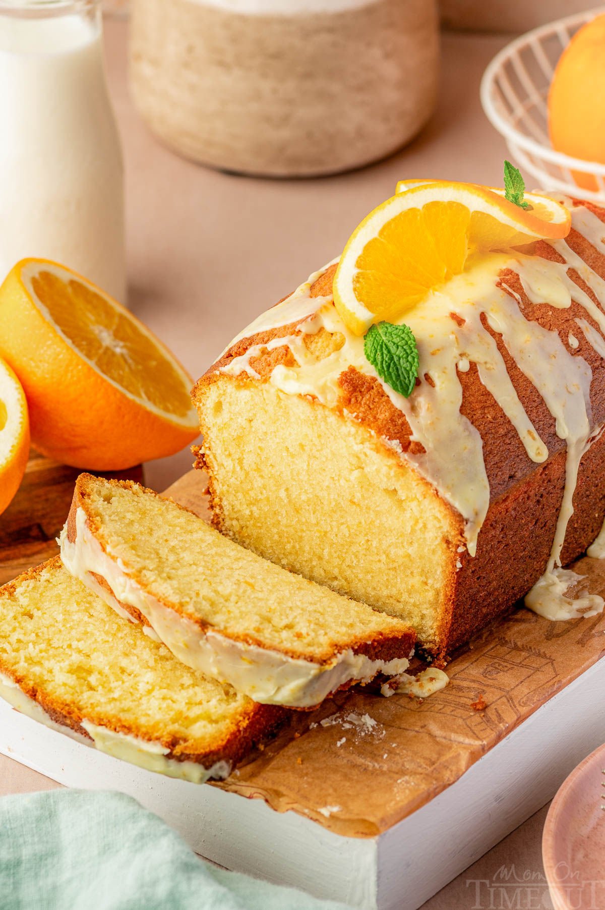 Top down angle shot of orange pound cake recipe topped with orange glaze on cutting board with two slices cut.