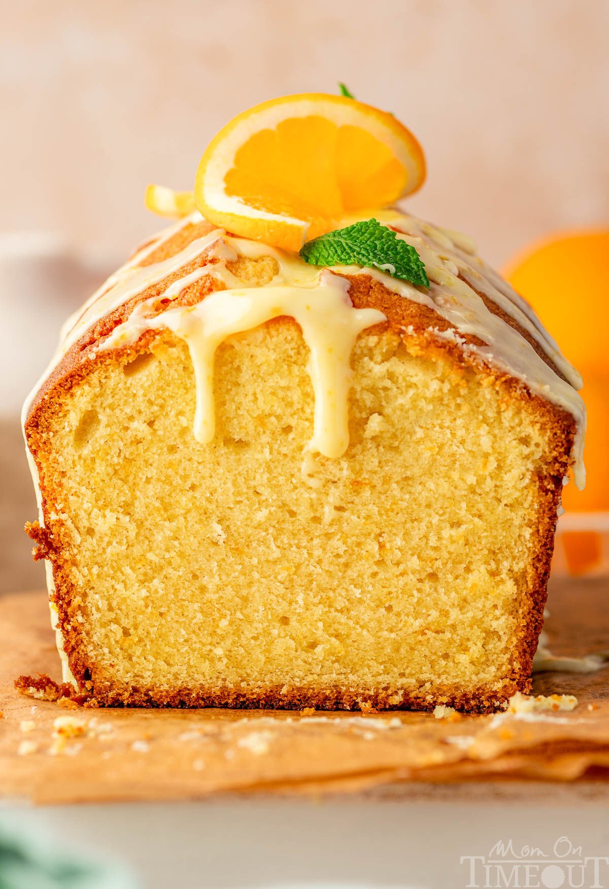 Orange pound cake with end cut off sitting on wood board topped with a glaze.