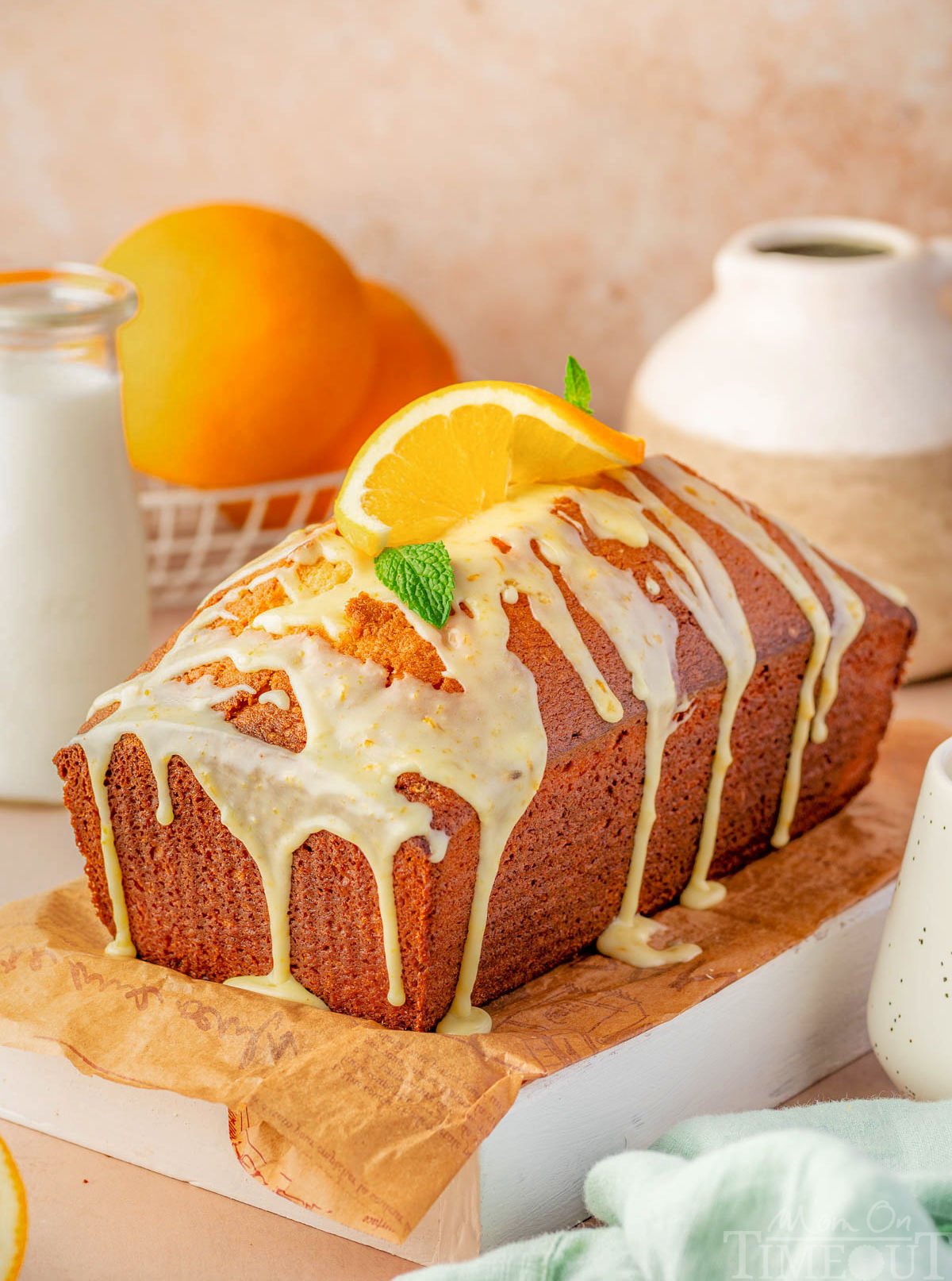 Whole orange pound cake with orange glaze sitting on wood cutting board ready to be enjoyed.