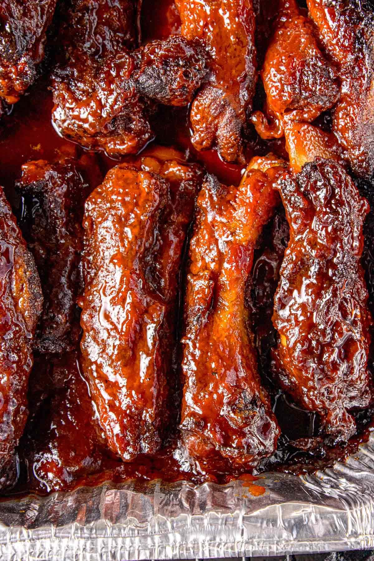 Close up overhead shot of party ribs in foil pan with shiny glaze.