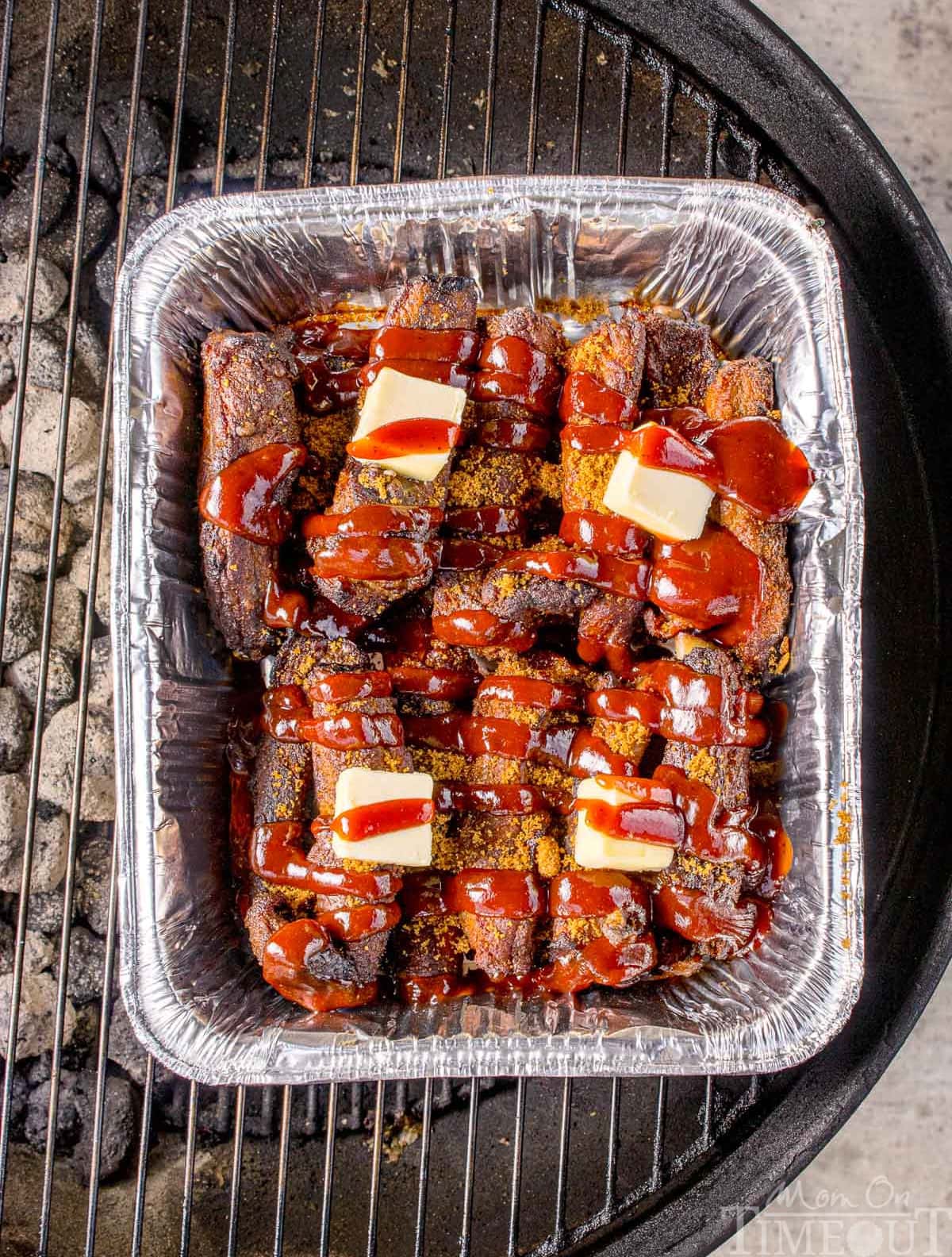 Overhead shot of party ribs recipe on the grill. Ribs are mixed with butter, seasonings and barbecue sauce.