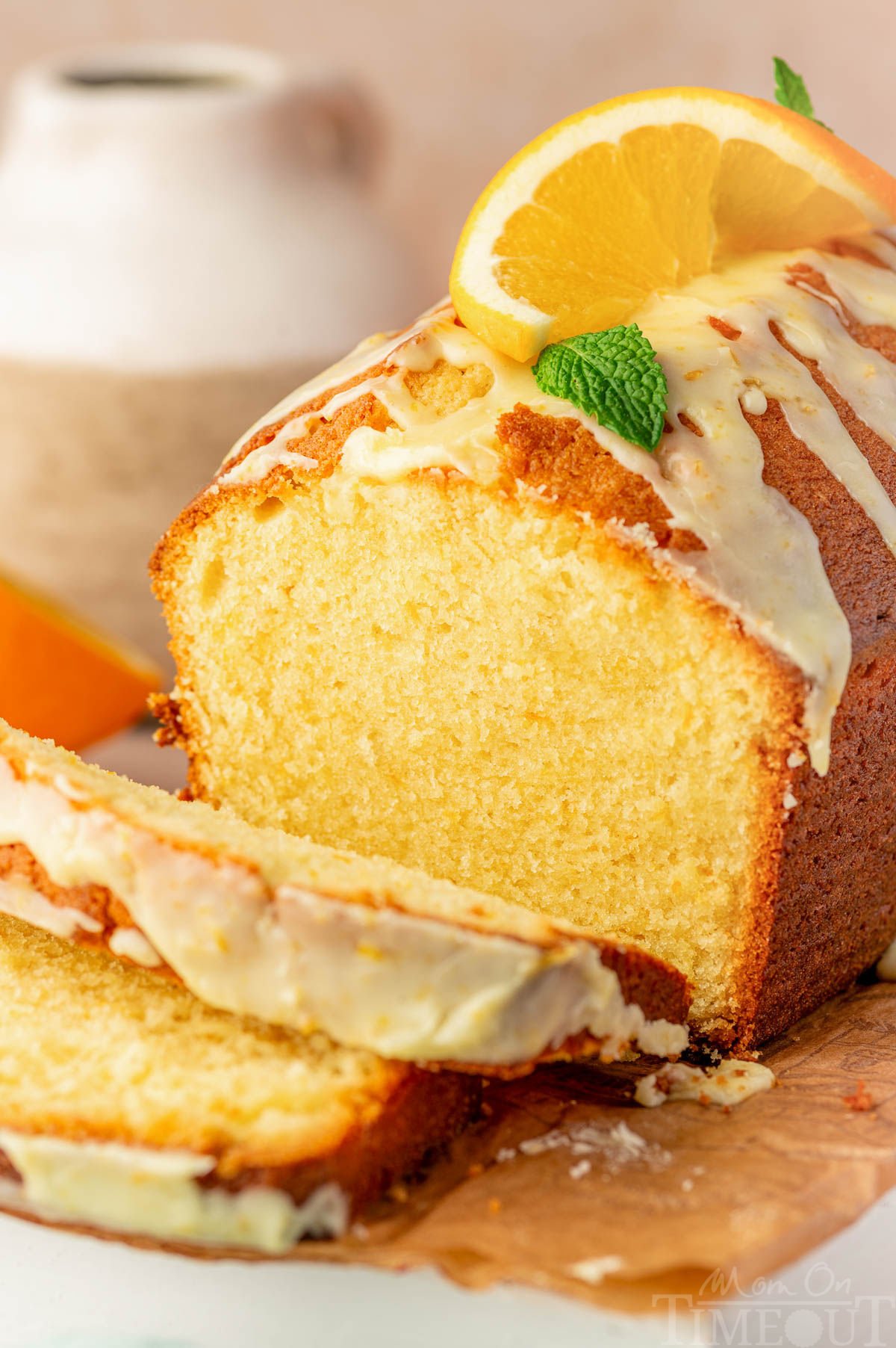 Angled shot of orange pound cake on cutting board with two slices cut off.