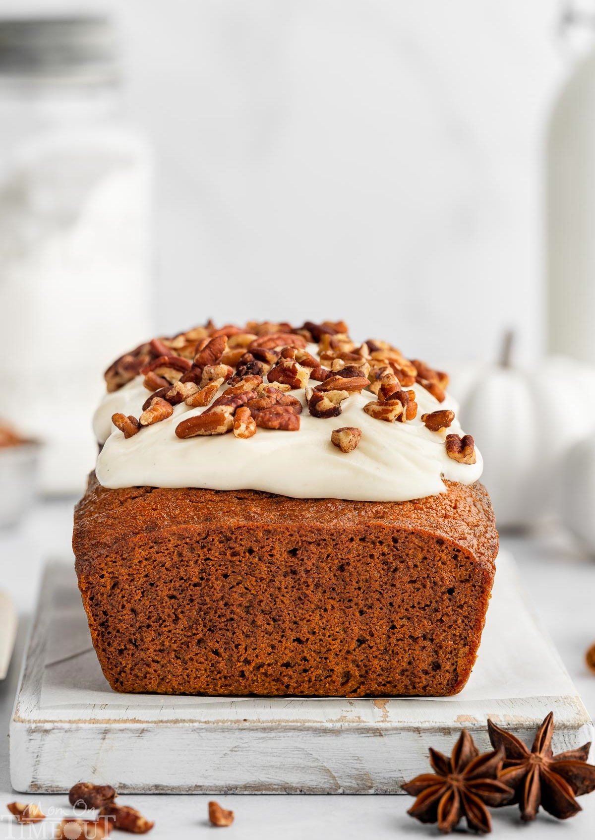 whole pumpkin loaf with cream cheese frosting sitting on white cutting board.