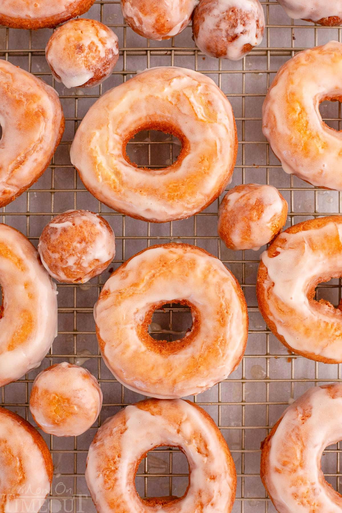 Overhead shot of sour cream cake donut on wire rack topped with glaze. 