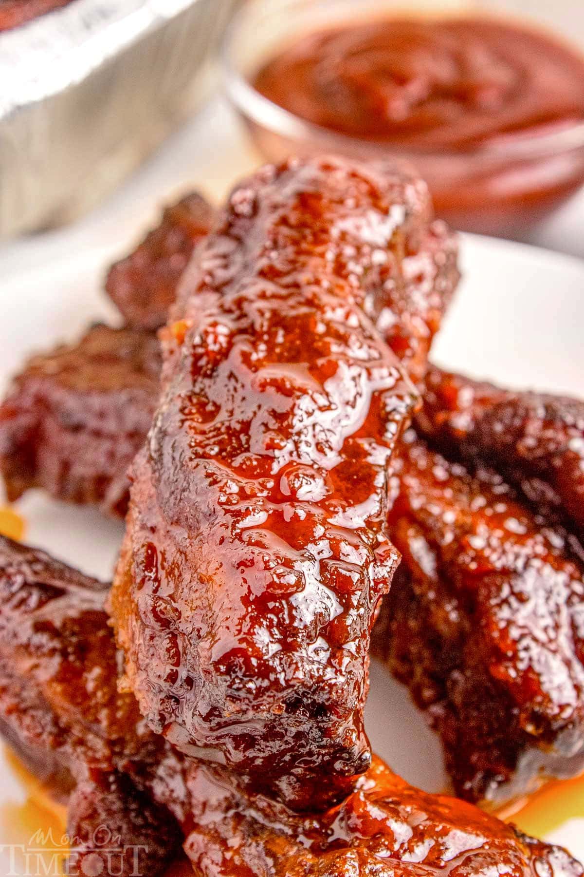 Four St. Louis party ribs on white plate with gorgeous saucy glaze.